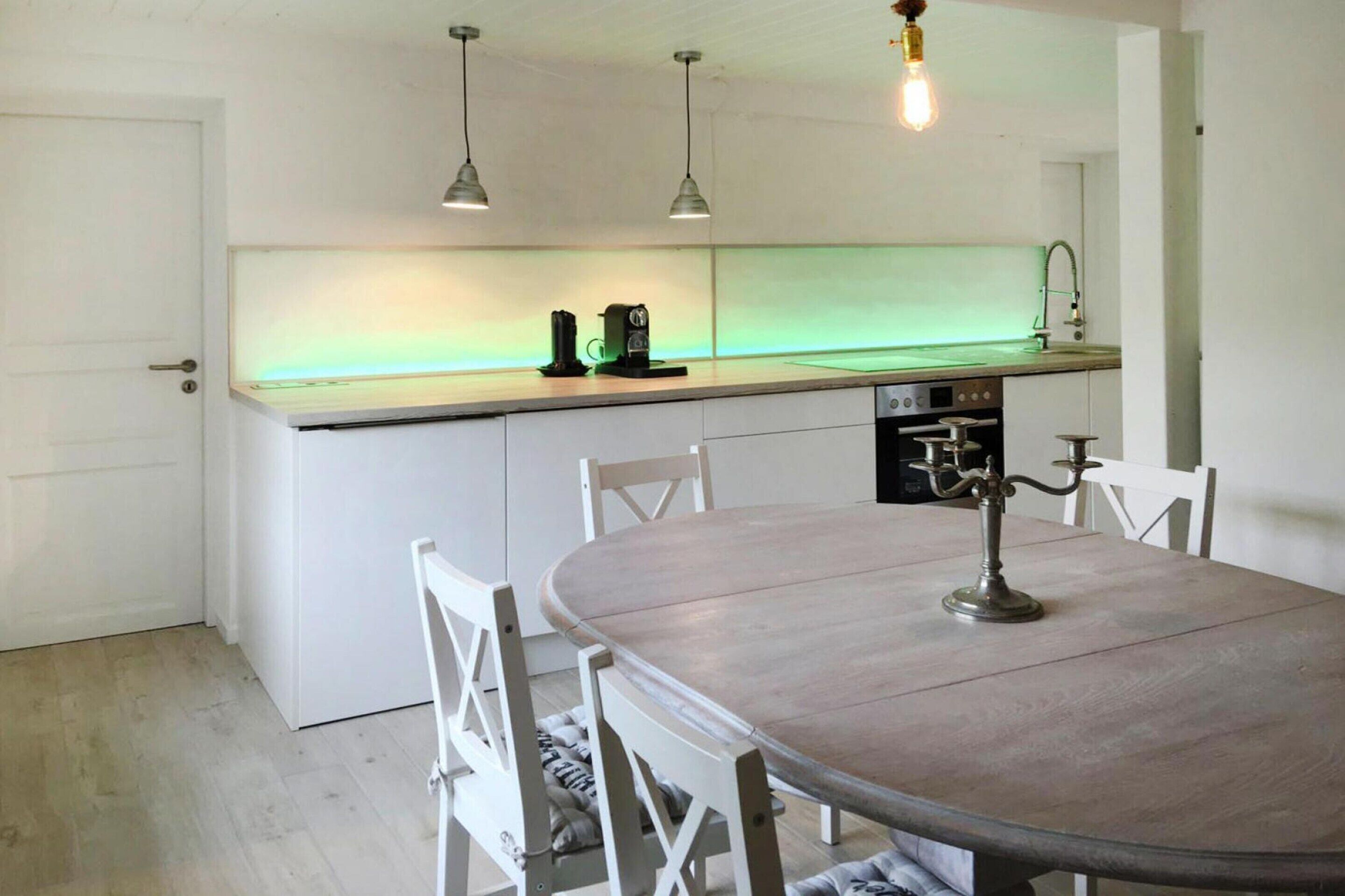 A kitchen with a round dining table, white chairs, and pendant lights.