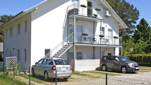 A two-story building with a balcony on the upper floor, a staircase leading to the entrance, and a car parked in front. - Appartementhaus, Zinnowitz (Zinnowitz)