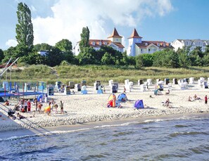 A beach with tents and beach chairs, a sandy shore, and buildings in the background. - Appartementhaus, Zinnowitz (Zinnowitz)