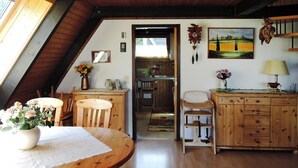 A cozy attic room with wooden furniture, a dining table with a vase of flowers, and a painting on the wall. - Ferienpark Tennenbronn (Schramberg)
