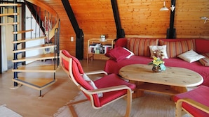 A cozy room with a wooden staircase, a red sofa set, and a wooden coffee table. - Ferienpark Tennenbronn (Schramberg)