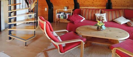 A cozy room with a wooden staircase, a red sofa set, and a wooden coffee table.