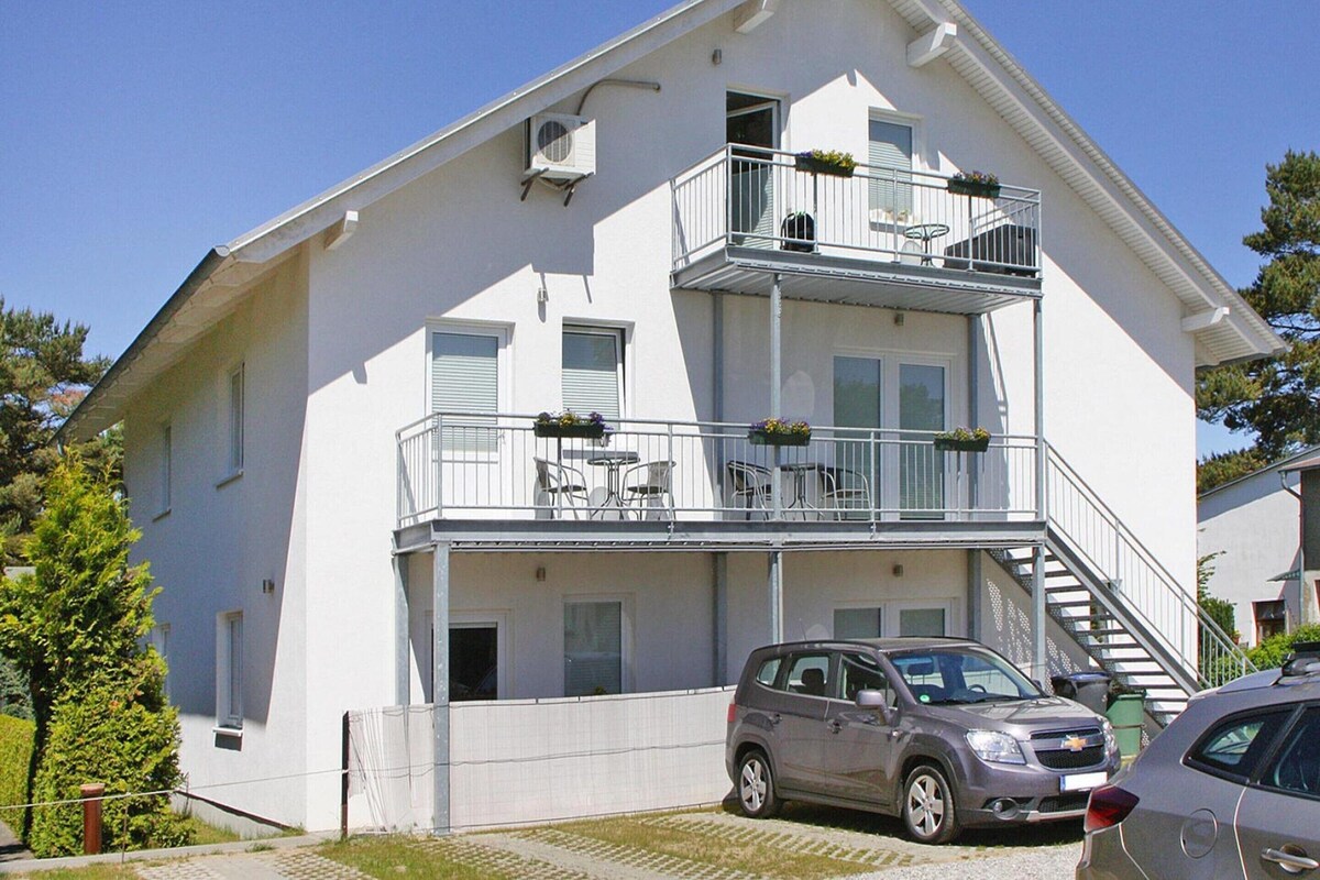 A two-story building with a balcony on the upper floor, a staircase to the upper level, and a car parked in front.