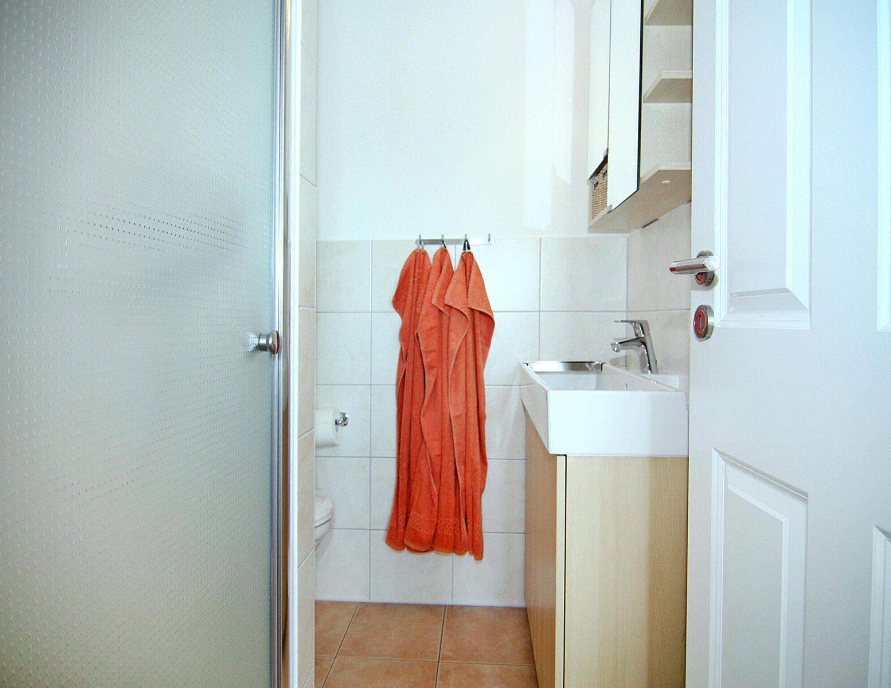 A bathroom with a toilet, a sink, and a towel rack with towels.