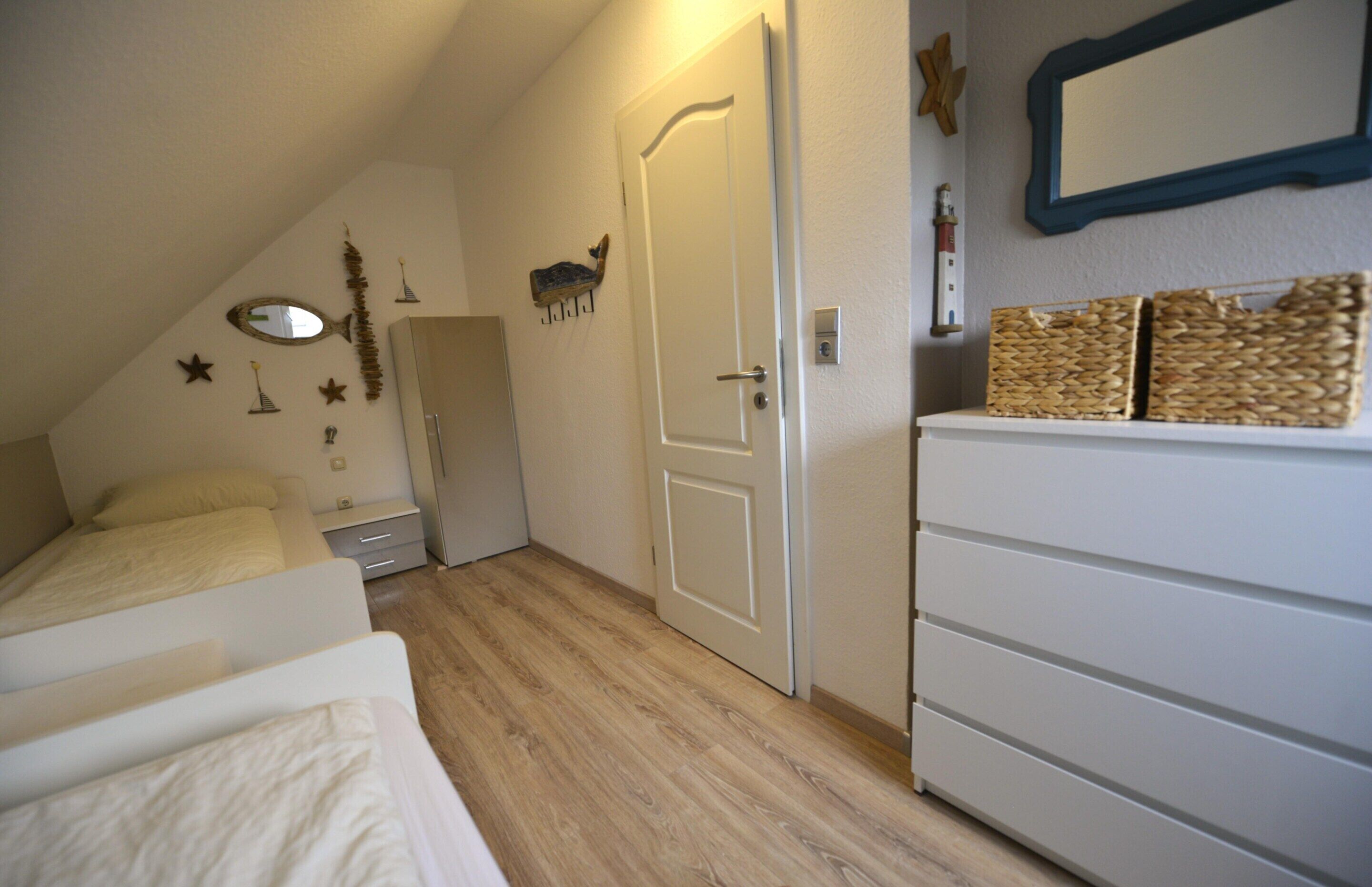 Un dormitorio con una cama, un armario, una puerta y un espejo en la pared.