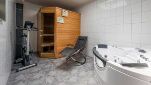 Ein Saunabereich mit einem Holfachbereich, einem Massagesessel und einer Massageliege.