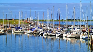 A marina with numerous boats docked, a grassy area in the background, and a clear sky. - Ferienwohnung in Wyk auf Foehr (Wyk auf Foehr)
