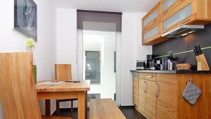 Una cocina compacta con armarios de madera, una encimera con electrodomésticos y un comedor con banco y sillas.