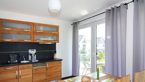 Una cocina moderna con armarios de madera, una encimera negra y un comedor con mesa y sillas de madera.