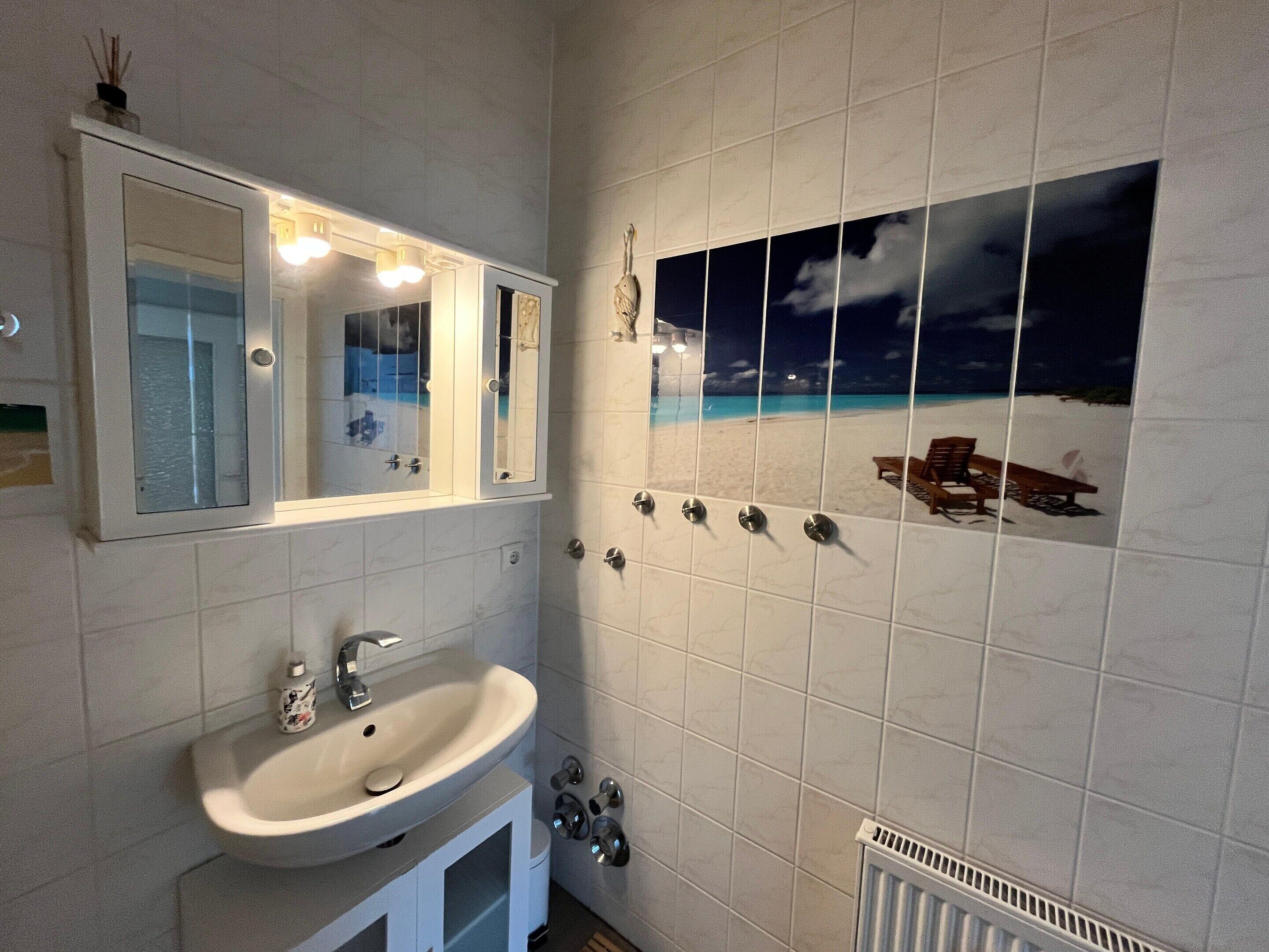 A bathroom with a sink, mirror, and a wall-mounted light fixture.
