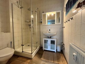 A modern bathroom with a glass-enclosed shower, a white sink, and a tiled floor. - Ferienwohnung Strandlaufer in Zinnowitz (Zinnowitz)