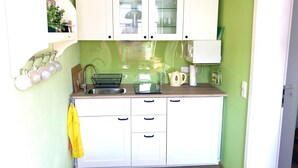 A compact kitchen with white cabinets, a sink, and a countertop. - Ferienwohnung Strandlaufer in Zinnowitz (Zinnowitz)