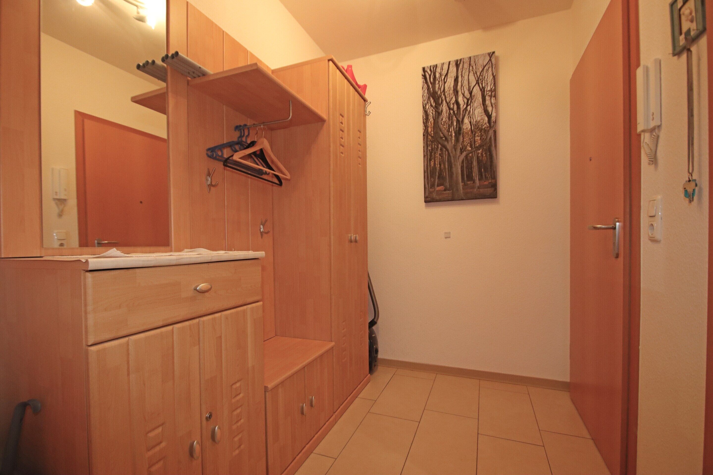 A room with wooden cabinets, a mirror, a painting, and a door.