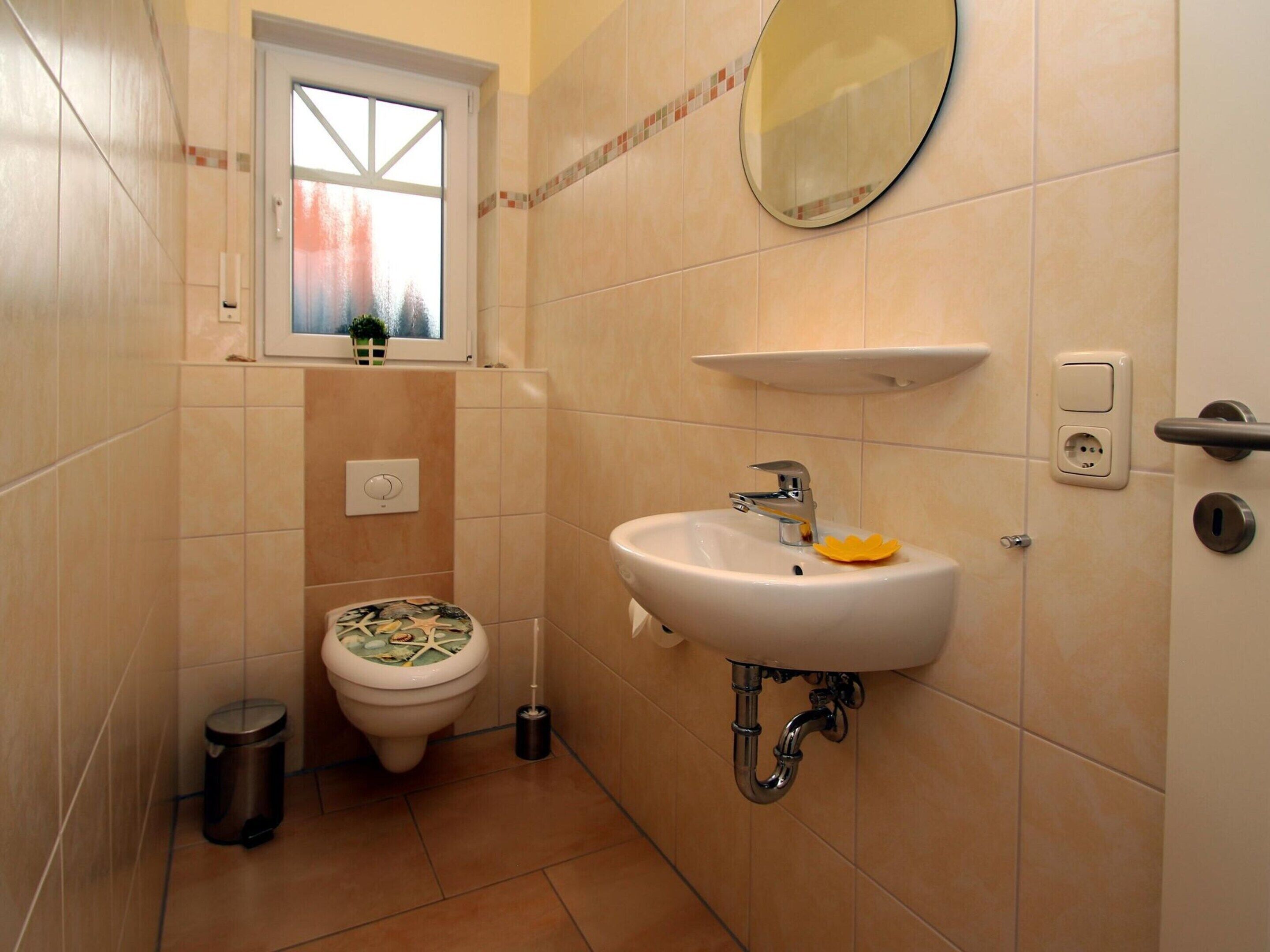 A bathroom with a toilet, sink, and window.
