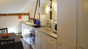 A compact kitchen with white cabinets, a built-in oven, a coffee maker, and a sink. - Ferienwohnung an der Elde (Luebz)