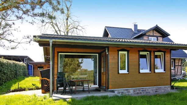 A modern house with a wooden exterior, a patio with outdoor furniture, and a large glass door leading to a covered area. - Ferienhaus Seeblick, Zemitz (Zemitz)