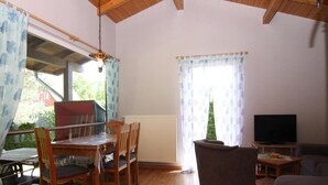 A dining area with wooden furniture, a television, and a window with curtains. - Ferienhaus Seeblick, Zemitz (Zemitz)
