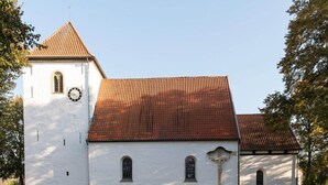 A white church with a red-tiled roof, a clock, and a statue in front. - Ferienhaus Seeblick, Zemitz (Zemitz)