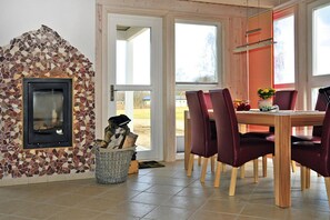 A dining area with a mosaic fireplace, a wooden table, and red chairs.