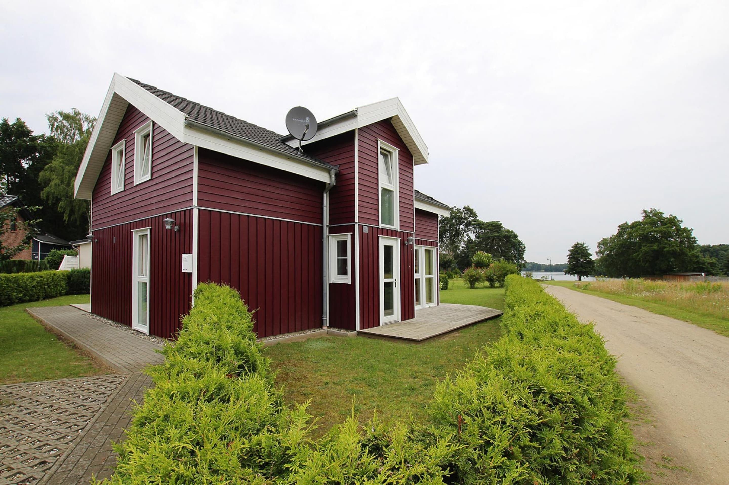 A two-story house with a red exterior, white trim, and a satellite dish on the roof.