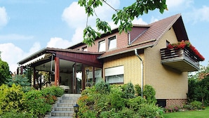 A two-story house with a covered porch, a brick exterior, and a small garden with steps leading to the entrance. - Holiday Home in Badenhausen (Bad Grund)
