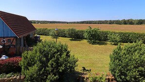 A barn with a red roof, a field in the background, and a clear blue sky. - Ferienwohnung, Wieck am Darss (Wieck auf dem Darss)