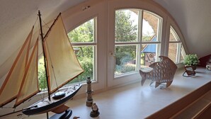 A room with a model sailboat, a rocking chair, and a potted plant. - Ferienwohnung, Wieck am Darss (Wieck auf dem Darss)
