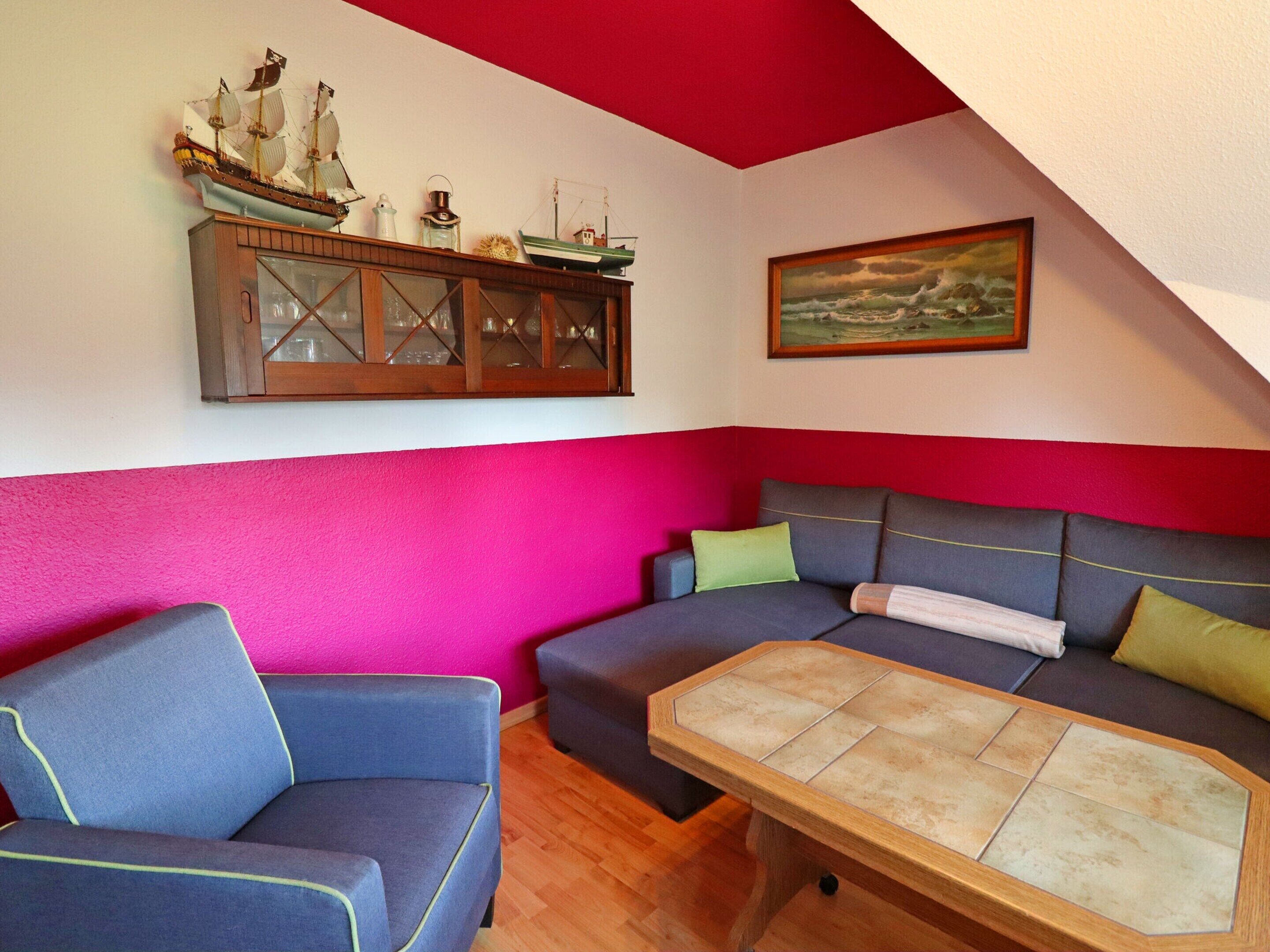 Een woonkamer met een blauwe bank, een houten salontafel en een plafond in rood en wit.