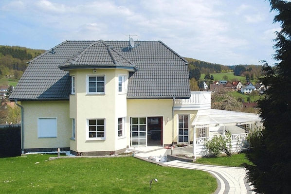 A two-story house with a sloped roof, a covered porch, and a well-maintained lawn. - Appartement im Fuchsbau in Bad Sachsa (Bad Sachsa)