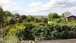 A residential area with houses, dense greenery, and a body of water in the background. - Ferienhaus, Krusendorf (Schwedeneck)