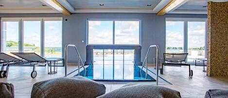 Amplio espacio interior con piscina, asientos y grandes ventanales que ofrecen vistas al exterior.