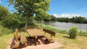 Ein Picknicktisch mit Bänken, umgeben von Gras und einem See.