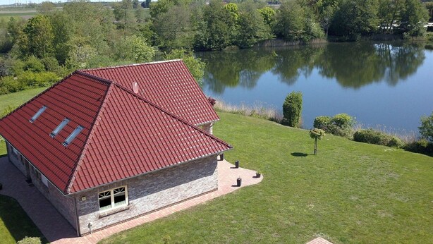 Ein Haus mit rotem Dach, Steinunterbau und befestigter Auffahrt.