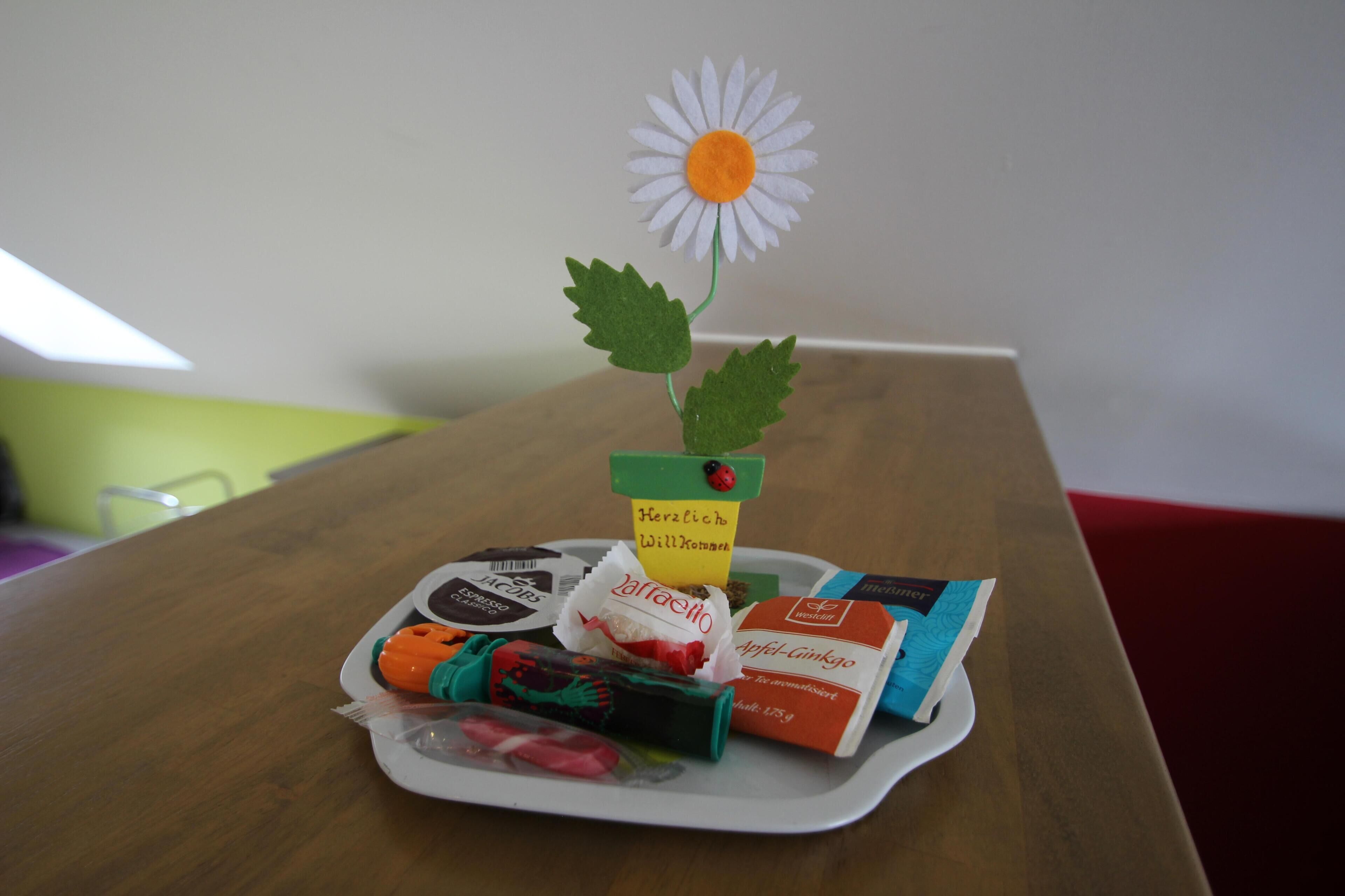 A tray with various food items and a paper flower decoration on a table.