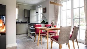 Una cocina moderna con armarios grises, una mesa de comedor de madera y sillas rojas.