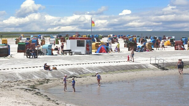 Une plage parsemée de nombreuses cabanes de plage colorées et dotée d’un poste de surveillance des sauveteurs.