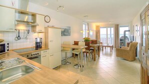 A modern kitchen with a dining area, a coffee machine, and a view of the sea. - Apartment in Rechin Right on the Water (Rechlin)
