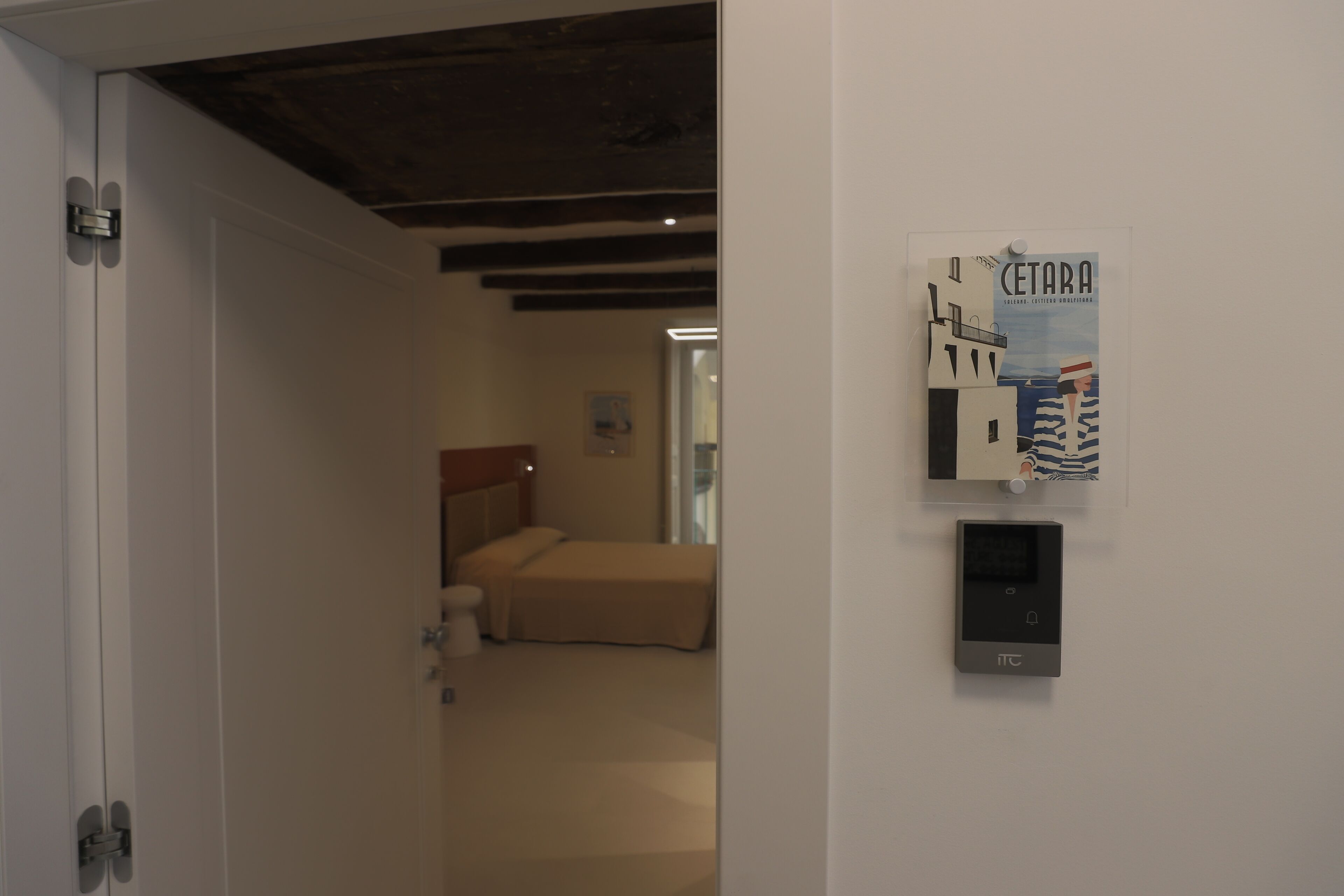 Une chambre d’hôtel avec un lit, un thermostat fixé au mur et une affiche accrochée au mur.