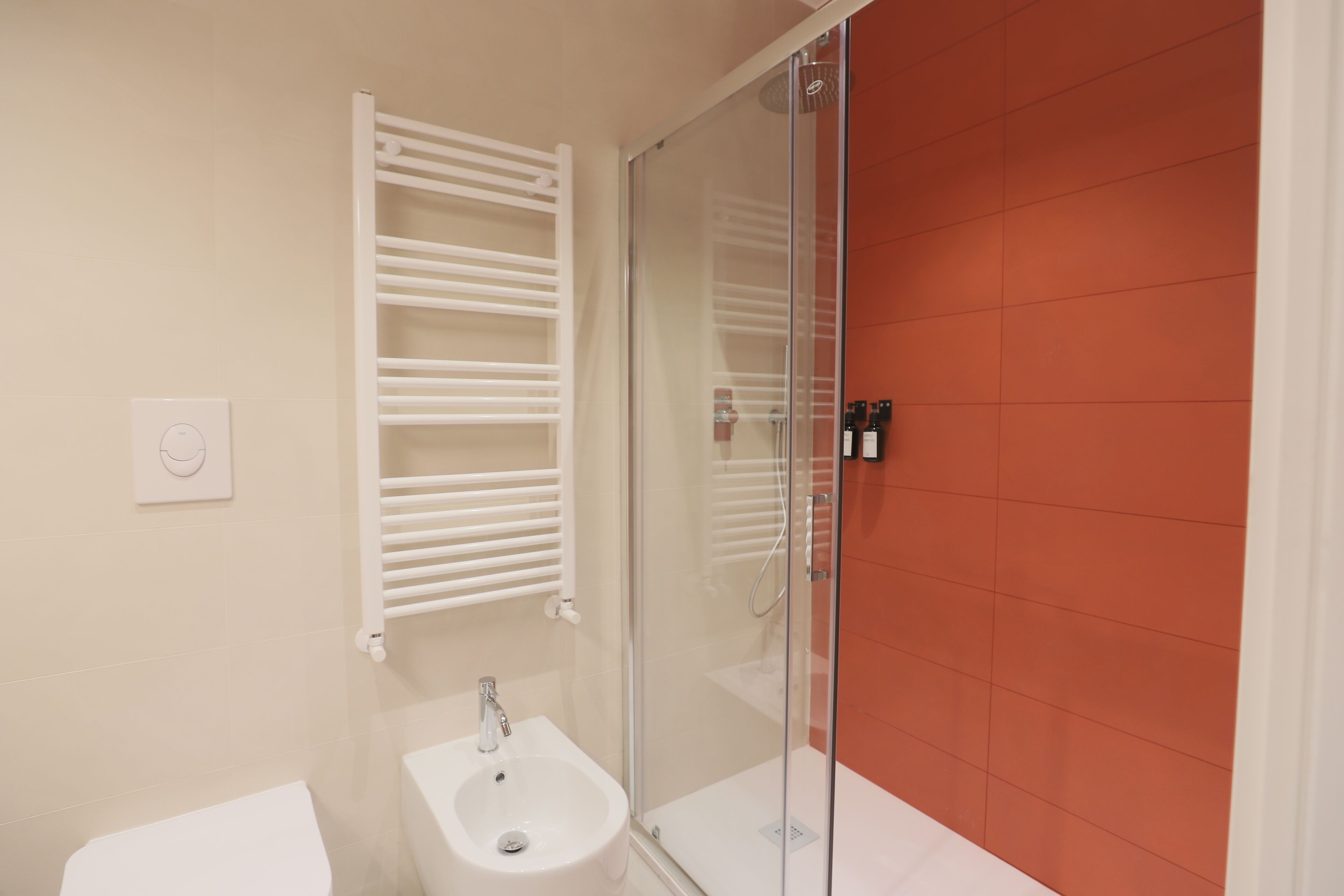 Een badkamer met een douchecabine van glas, een witte wastafel en een handdoekhouder.