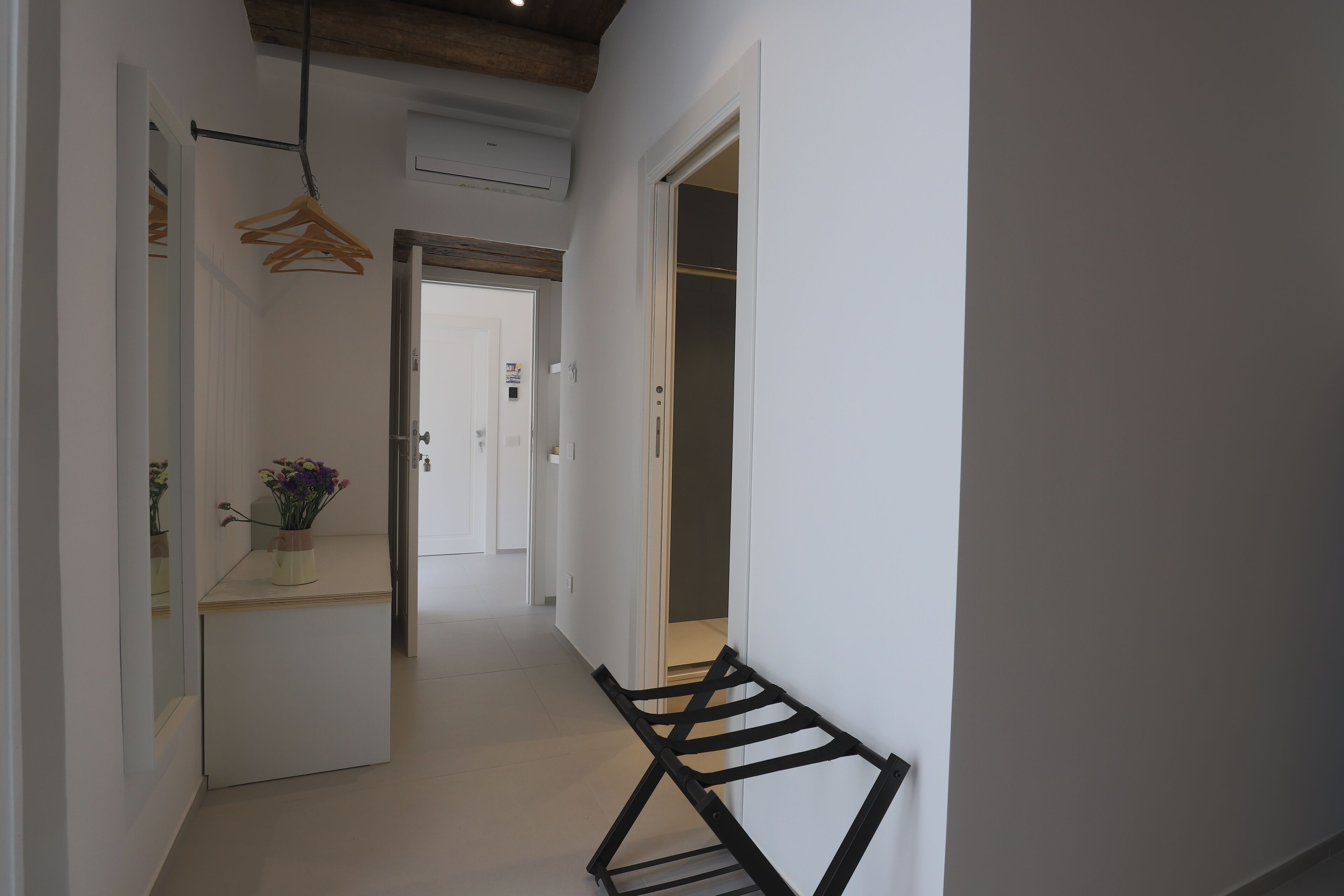 A hallway with a bench, a mirror, and a hanging rack.