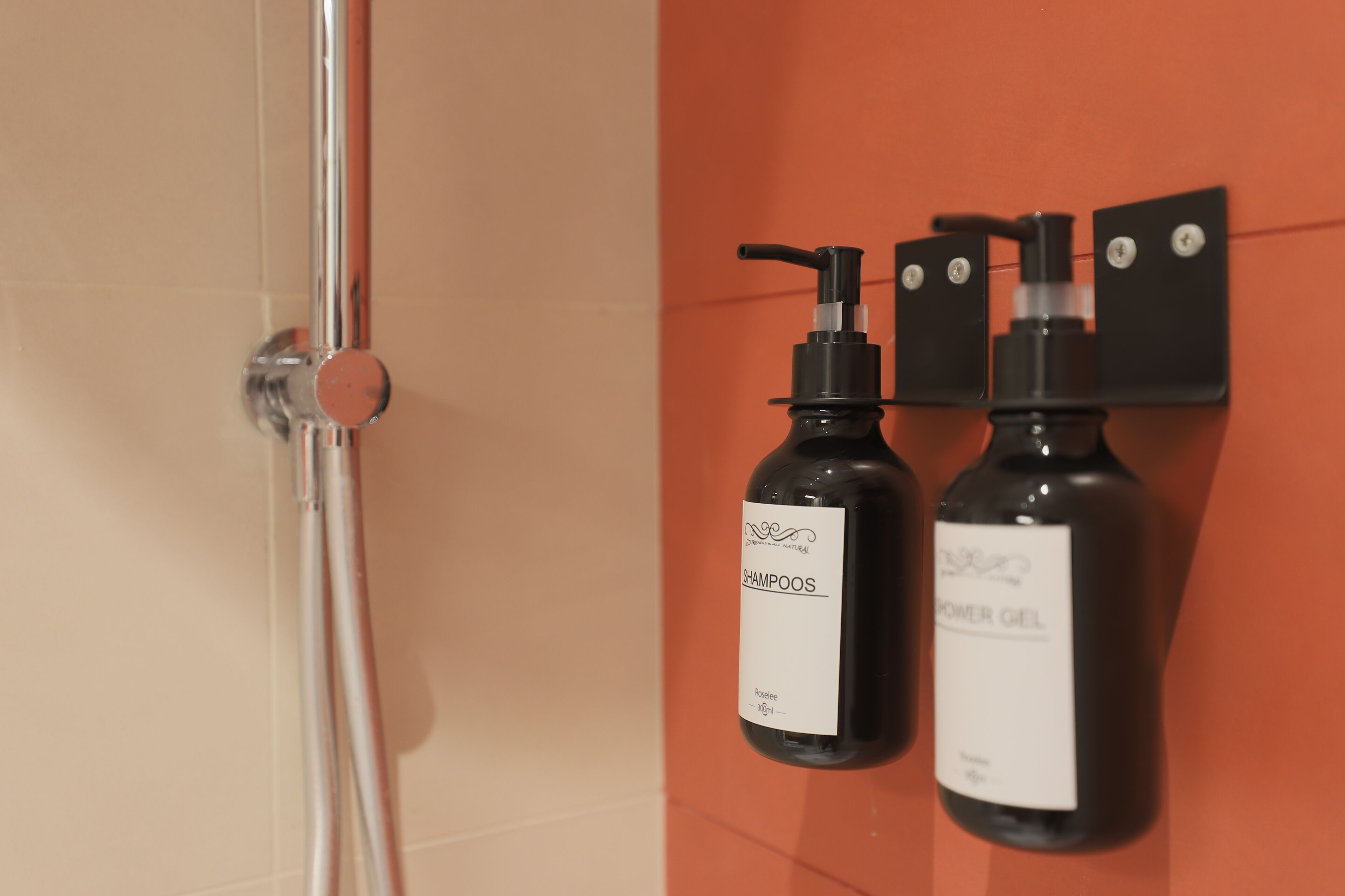 Ein Badezimmer mit Dusche und zwei Flaschen Shampoo und Duschgel an der Wand.