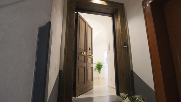 A hallway with a wooden door leading to a room. - DESIDERIO GUEST HOUSE (Salerno)