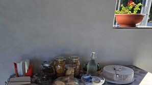 Una mesa con un mantel estampado, frascos de comida, un plato de galletas, una botella y un pastel.