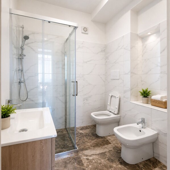 A bathroom with a glass shower enclosure, a toilet, a bidet, and a sink with a mirror. - b&b Miramare (Ascea)