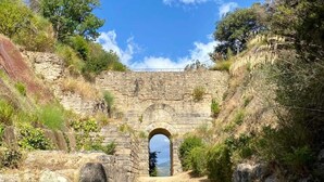 Un arco de piedra que da paso a un paisaje natural.