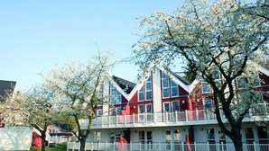 Un edificio de varios pisos con una decoración en rojo y blanco, que cuenta con balcones y ventanas amplias.