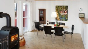 Una cocina moderna con una estufa de leña, una mesa de comedor con sillas, un armario y un cuadro en la pared.