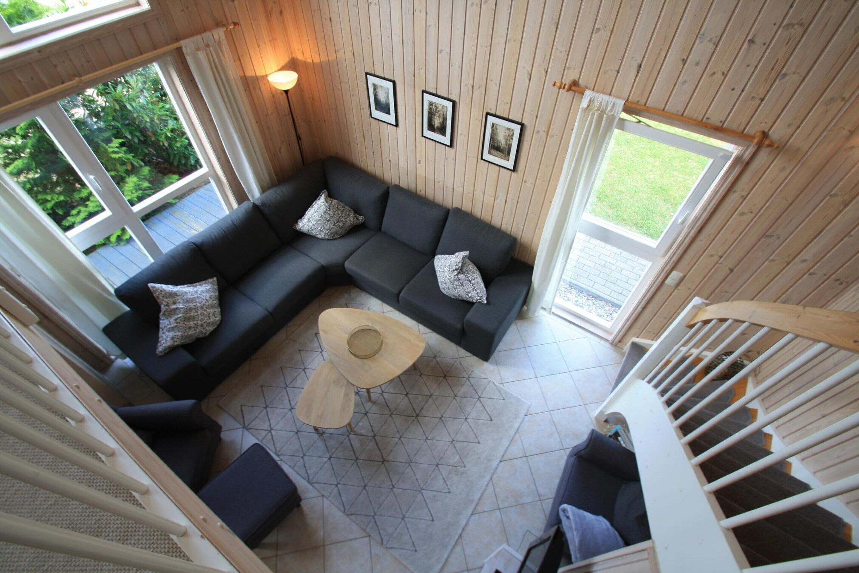 A modern living room with a sectional sofa, a round coffee table, and a staircase.