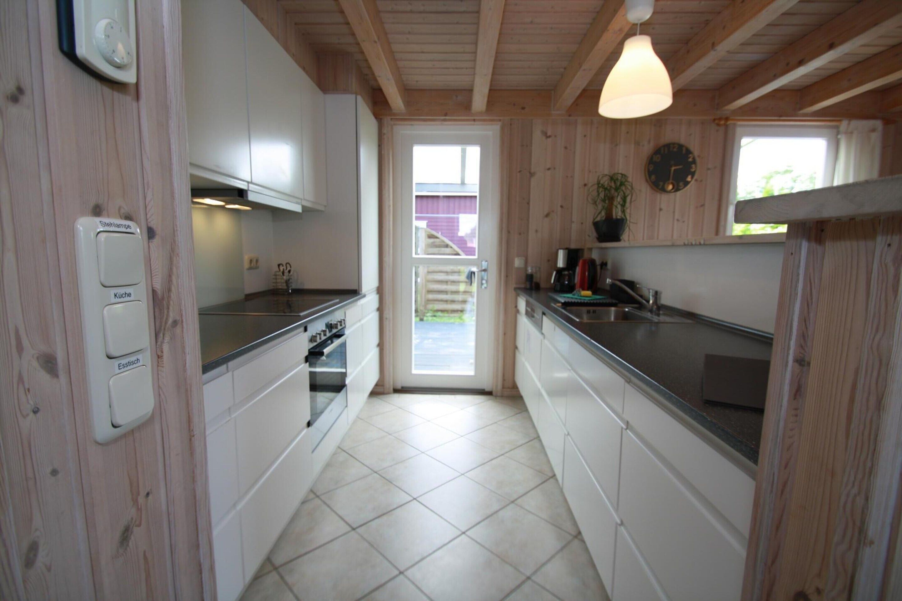 A kitchen with wooden walls, white cabinets, a stove, and a sink.