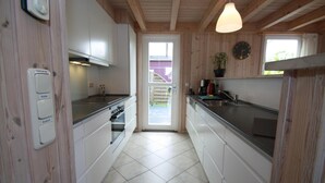 A kitchen with wooden walls, white cabinets, a stove, and a sink. - Ferienhaus Seeidyll am Dummer See, Dummer (Dümmer)